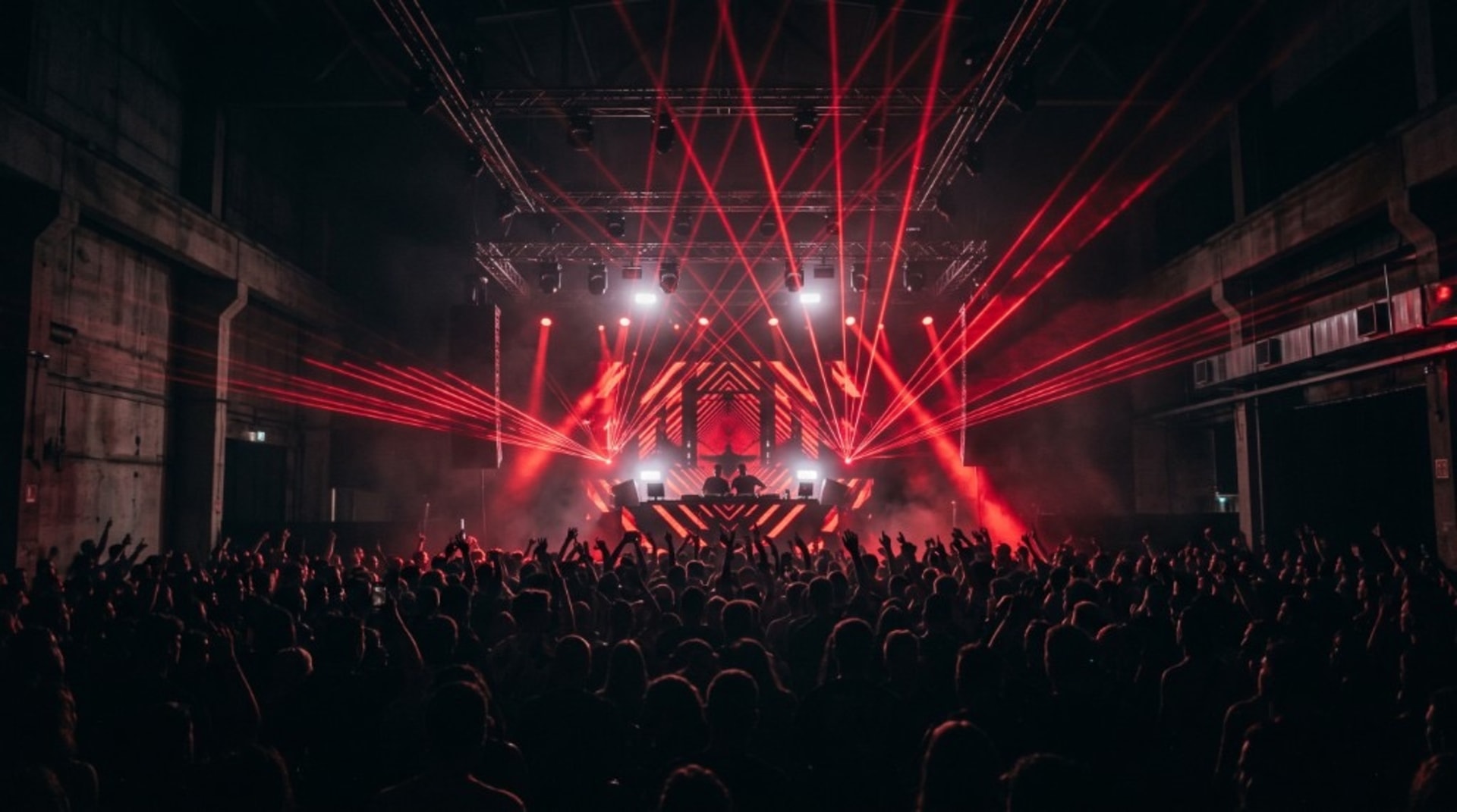 Pista lotada iluminada por lasers vermelhos em um show de música eletrônica